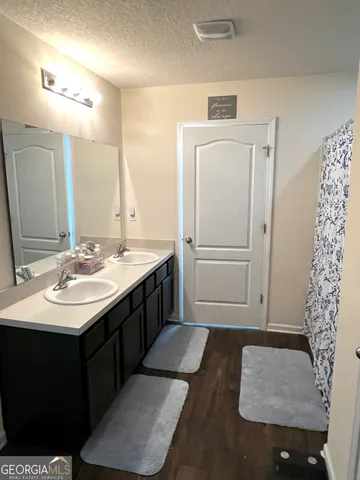a bathroom with a double vanity sink a toilet a mirror and shower