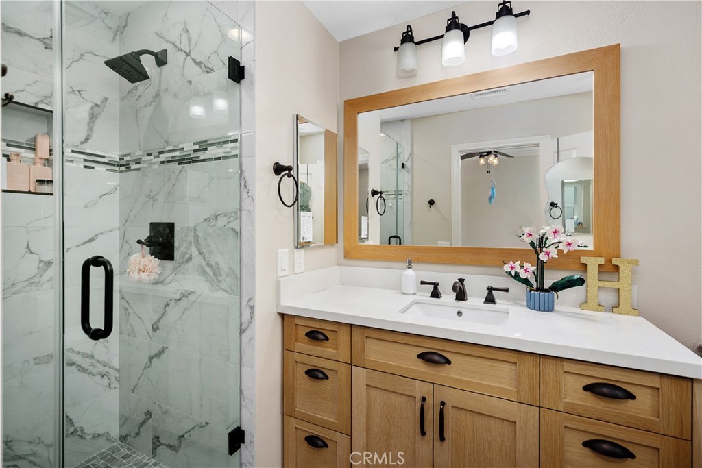 27121 Woodbluff Road Laguna Hills, CA 92653 - Photo 18 of 30 a bathroom with a double vanity sink a mirror a glass door a shower and vanity