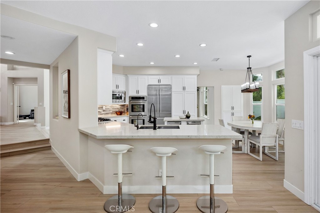 27121 Woodbluff Road Laguna Hills, CA 92653 - Photo 10 of 30 a kitchen with stainless steel appliances kitchen island granite countertop a dining table chairs and white cabinets