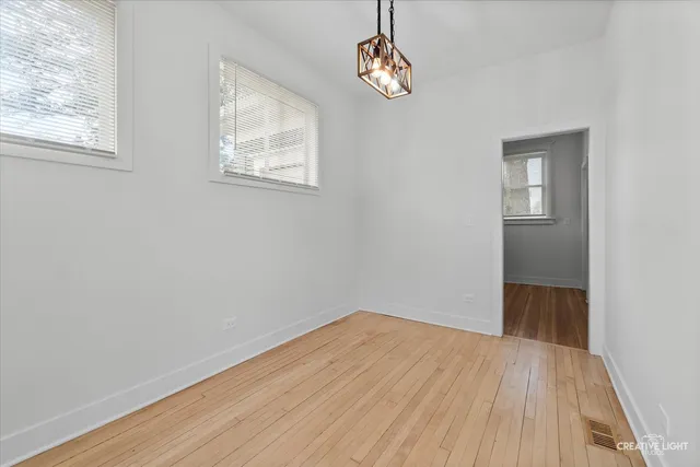 a view of empty room with wooden floor and window