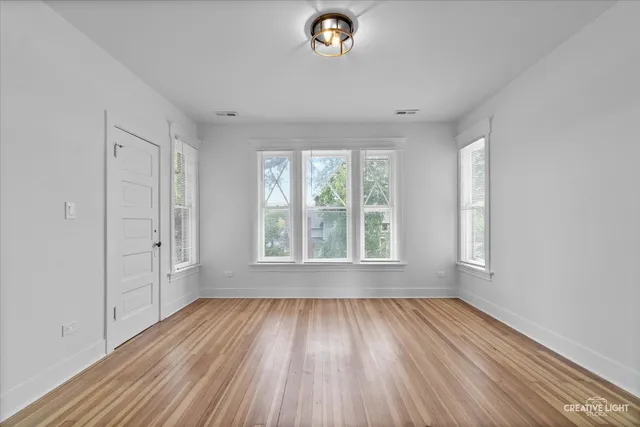 an empty room with windows and wooden floor