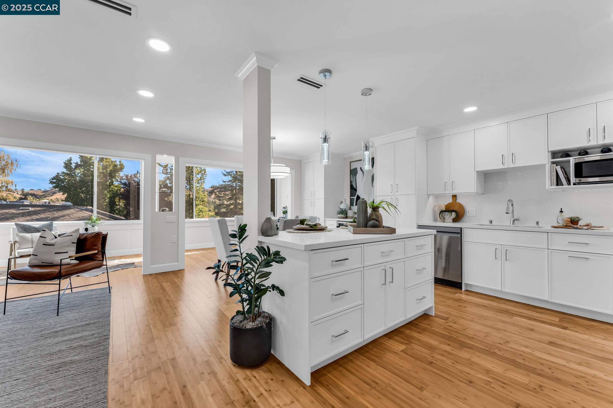 a room with stainless steel appliances kitchen island granite countertop a stove a sink a refrigerator and white cabinets with wooden floor