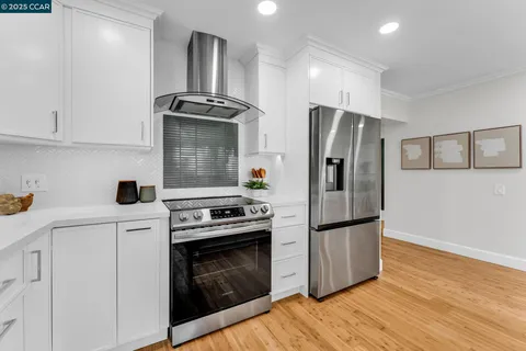 a kitchen with stainless steel appliances granite countertop a refrigerator stove and white cabinets
