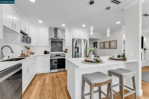 a kitchen with stainless steel appliances kitchen island granite countertop a stove a refrigerator a oven a sink a table and chairs