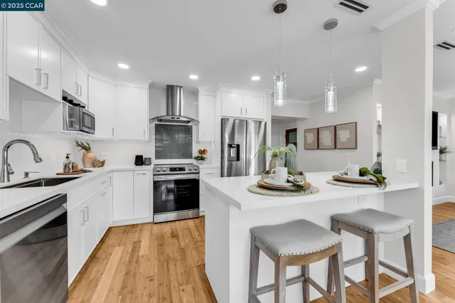 a kitchen with stainless steel appliances kitchen island granite countertop a stove a refrigerator a oven a sink a table and chairs