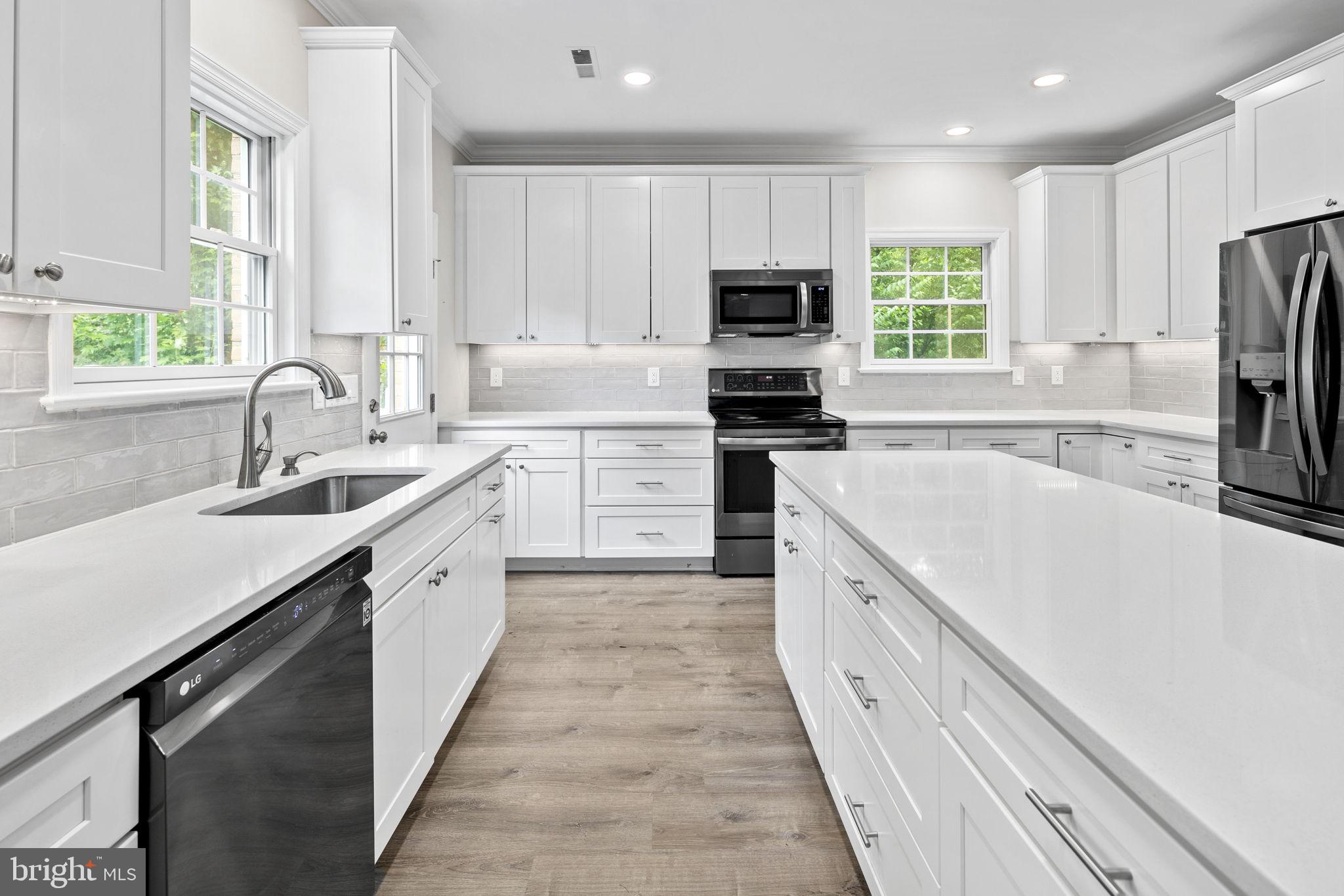 6916 Seven Locks Road Cabin John, MD 20818 - Photo 20 of 38 a large kitchen with stainless steel appliances granite countertop a sink dishwasher a stove and a refrigerator with wooden floor