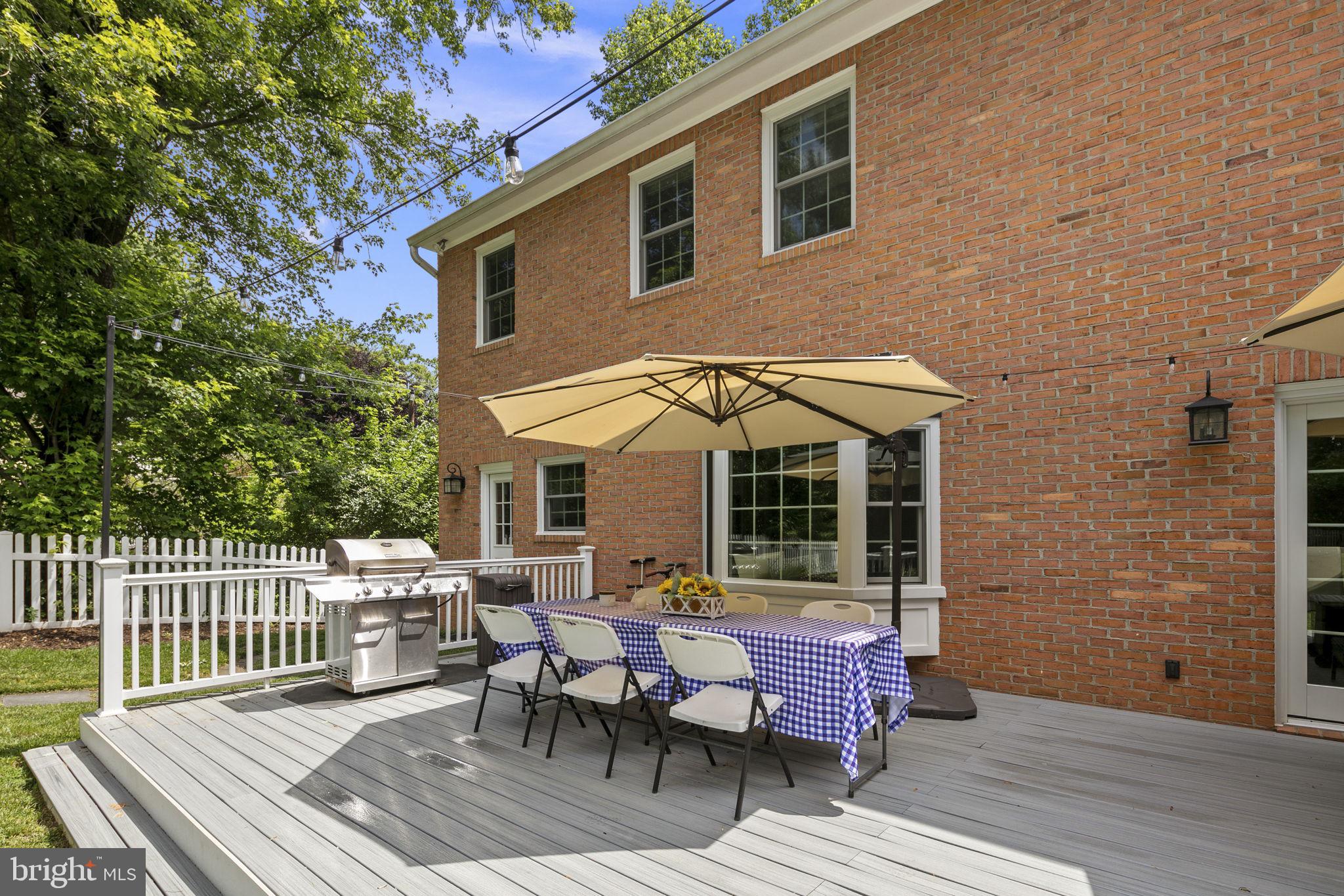 6916 Seven Locks Road Cabin John, MD 20818 - Photo 27 of 38 a backyard of a house with a barn table and chairs with wooden floor and fence