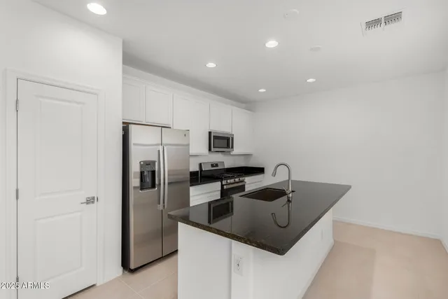 a kitchen with granite countertop a stove sink and refrigerator