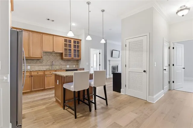 a kitchen with stainless steel appliances granite countertop a refrigerator a sink a stove a dining table and chairs