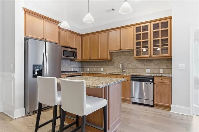 a kitchen with kitchen island granite countertop a sink cabinets and stainless steel appliances