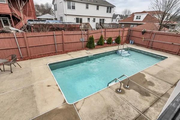 a view of a roof deck with table and chairs under an umbrella with a barbeque grill and couches