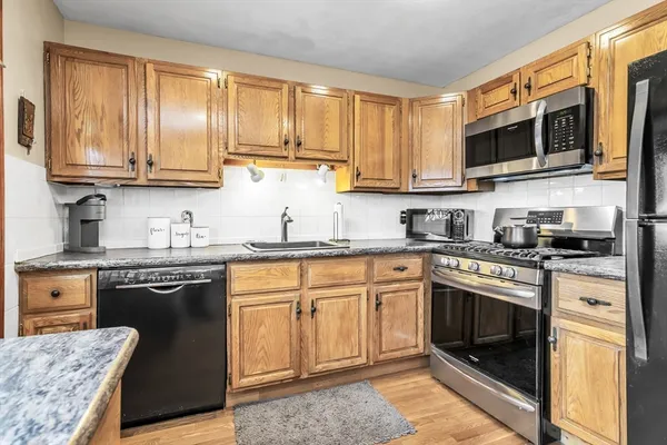 a kitchen with stainless steel appliances granite countertop a stove top oven a sink dishwasher and white cabinets