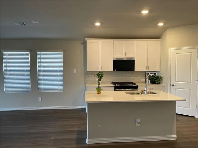 a kitchen with kitchen island granite countertop a sink stove and microwave