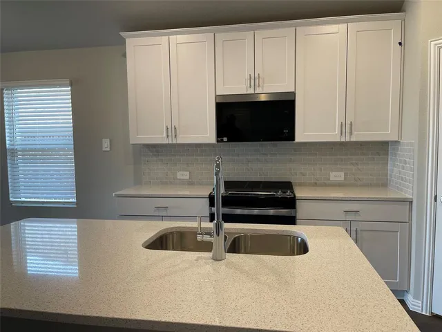 a kitchen with white cabinets and stainless steel appliances
