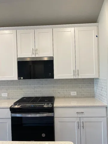a kitchen with granite countertop white cabinets and black appliances