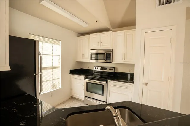 a kitchen with granite countertop a stove a sink and a microwave