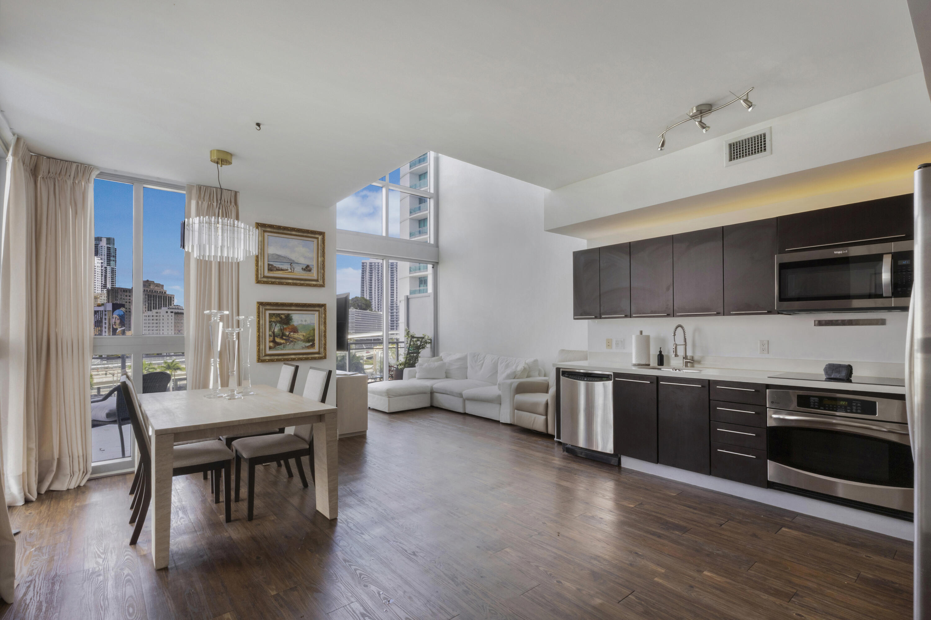 90 Southwest 3rd Street, Unit TH700A Miami, FL 33130 - Photo 2 of 32 a living room with stainless steel appliances a kitchen island hardwood floor sink stove dining table and chairs