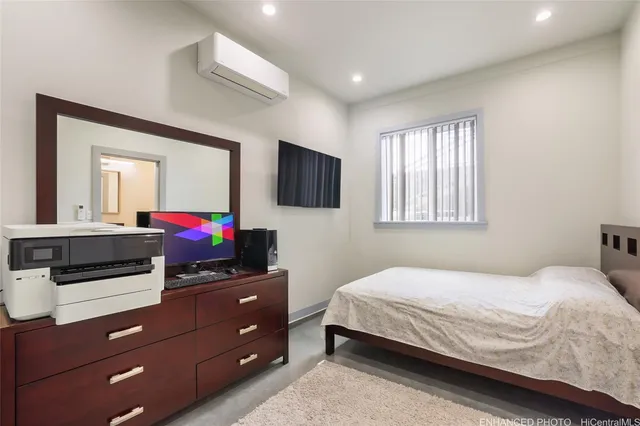 a bedroom with a bed and a flat tv screen on dresser