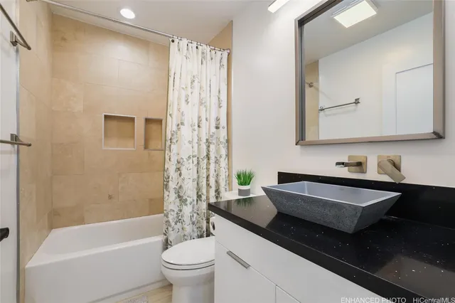 a bathroom with a granite countertop bathtub sink vanity mirror and toilet