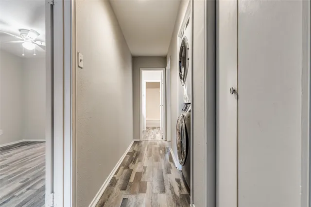 a view of a hallway with wooden floor and a bathroom