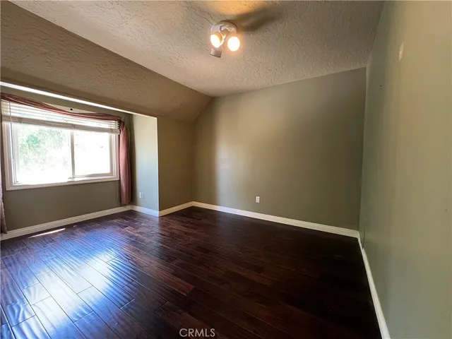 a view of a refrigerator in kitchen and an empty room with wooden floor windows
