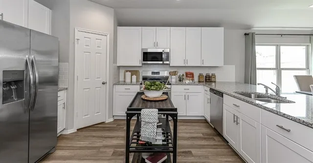a kitchen with white cabinets stainless steel appliances a sink and a window