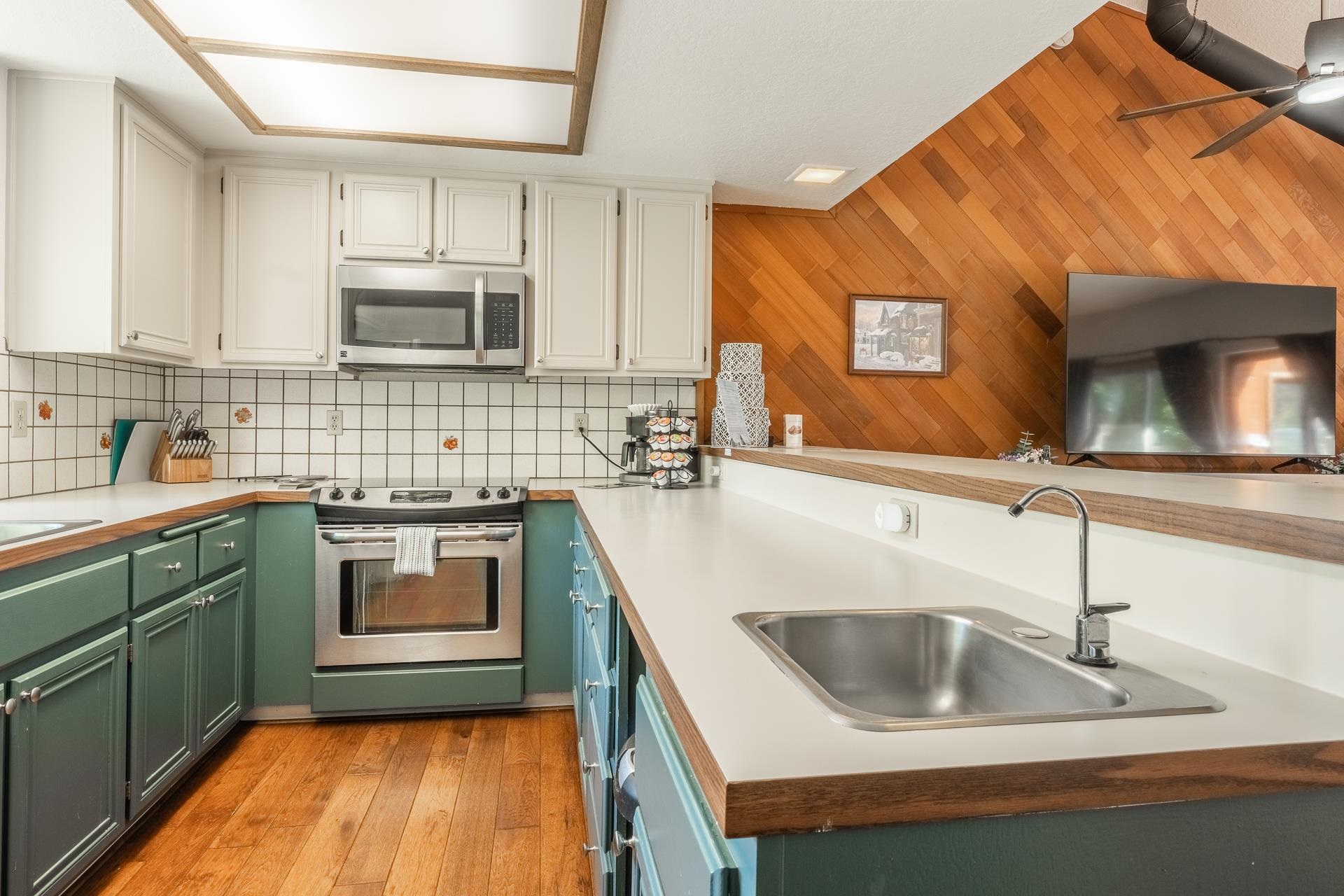 354 Joaquin Road, Unit 4 Mammoth Lakes, CA 93546 - Photo 13 of 40 Kitchen featuring stainless steel appliances, green cabinets, backsplash, white cabinets, and wooden walls