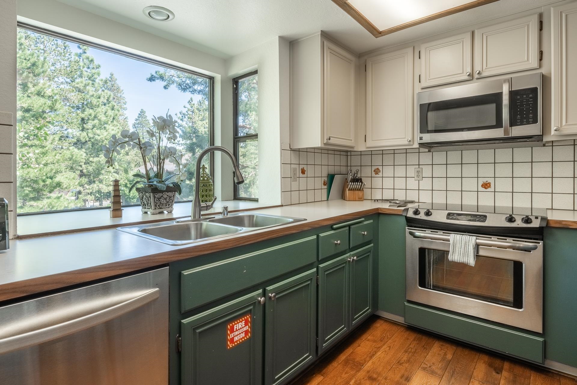 354 Joaquin Road, Unit 4 Mammoth Lakes, CA 93546 - Photo 14 of 40 Kitchen featuring appliances with stainless steel finishes, green cabinetry, decorative backsplash, and dark wood finished floors