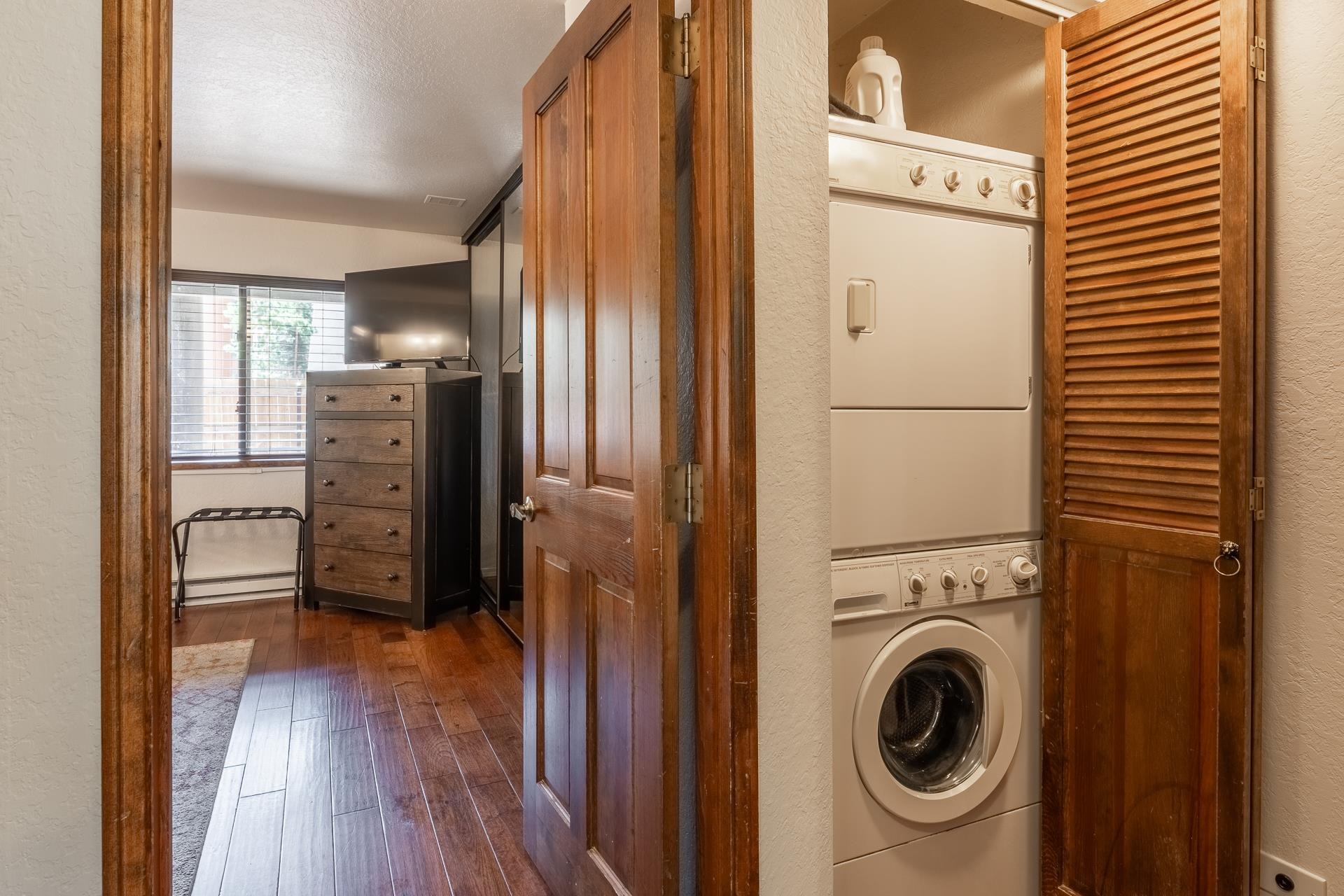 354 Joaquin Road, Unit 4 Mammoth Lakes, CA 93546 - Photo 28 of 40 Laundry room featuring estacked washer and dryer, dark wood finished floors, a textured wall, and a baseboard heating unit