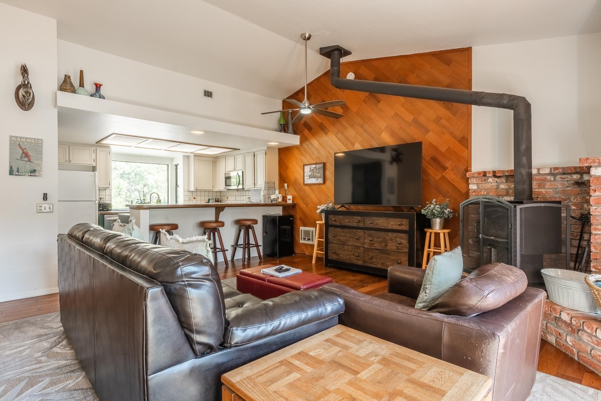 354 Joaquin Road, Unit 4 Mammoth Lakes, CA 93546 - Photo 5 of 40 Living area featuring a wood stove, vaulted ceiling, a ceiling fan, wood finished floors, and wooden walls