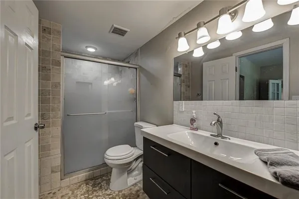 a bathroom with a granite countertop toilet sink and mirror