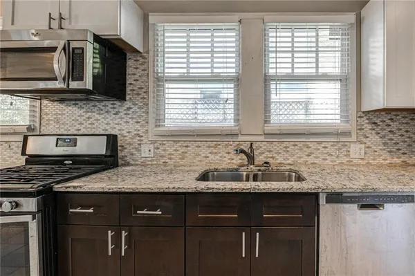 a kitchen with stainless steel appliances granite countertop a stove a sink and a microwave