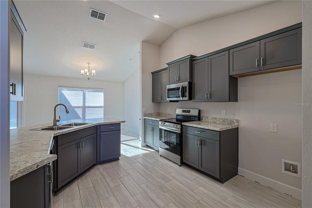 10939 Southwest 41st Avenue Ocala, FL 34476 - Photo 13 of 40 a kitchen with stainless steel appliances granite countertop a sink stove and refrigerator