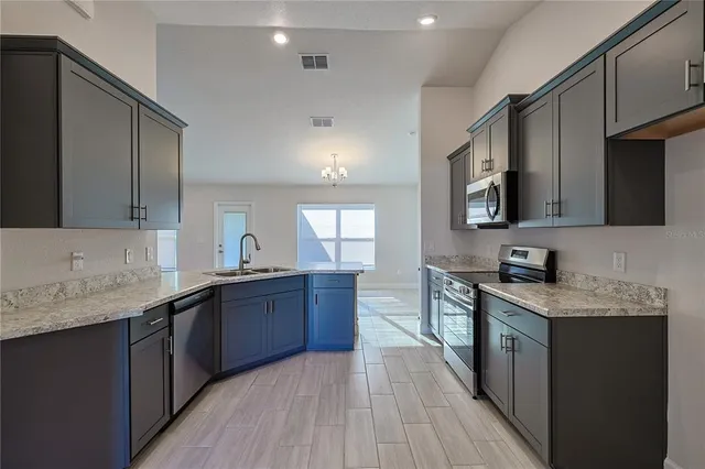 a large kitchen with stainless steel appliances granite countertop a sink stove and microwave