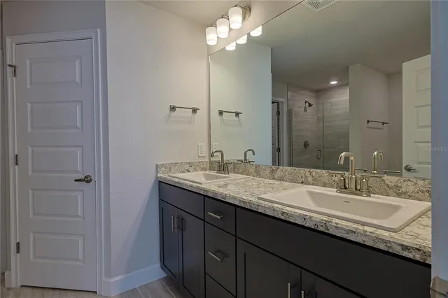 a bathroom with a granite countertop sink a light fixture and a mirror