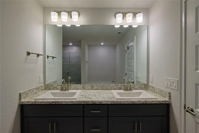 a bathroom with a granite countertop sink a large mirror and a light fixture