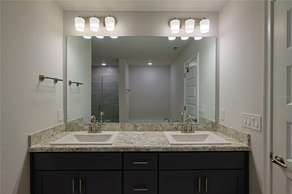 10939 Southwest 41st Avenue Ocala, FL 34476 - Photo 33 of 40 a bathroom with a granite countertop sink a large mirror and a light fixture