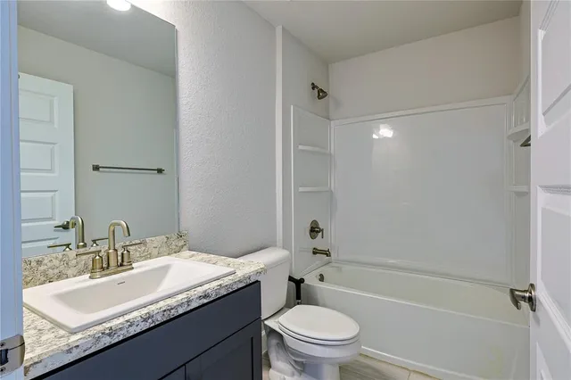 a bathroom with a granite countertop sink toilet mirror and shower