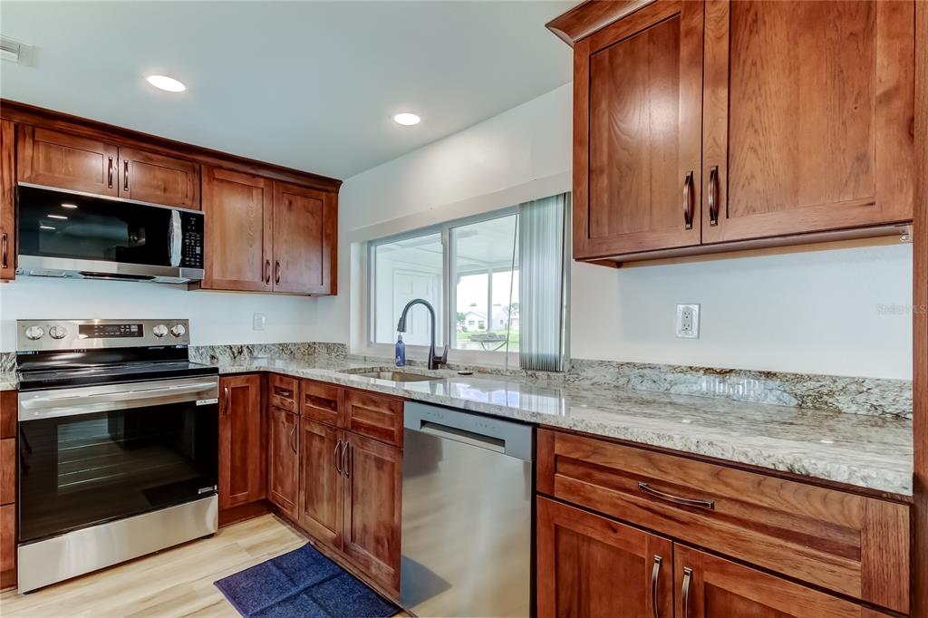 3625 Delta Place Holiday, FL 34691 - Photo 8 of 48 a kitchen with granite countertop stainless steel appliances a stove microwave and sink