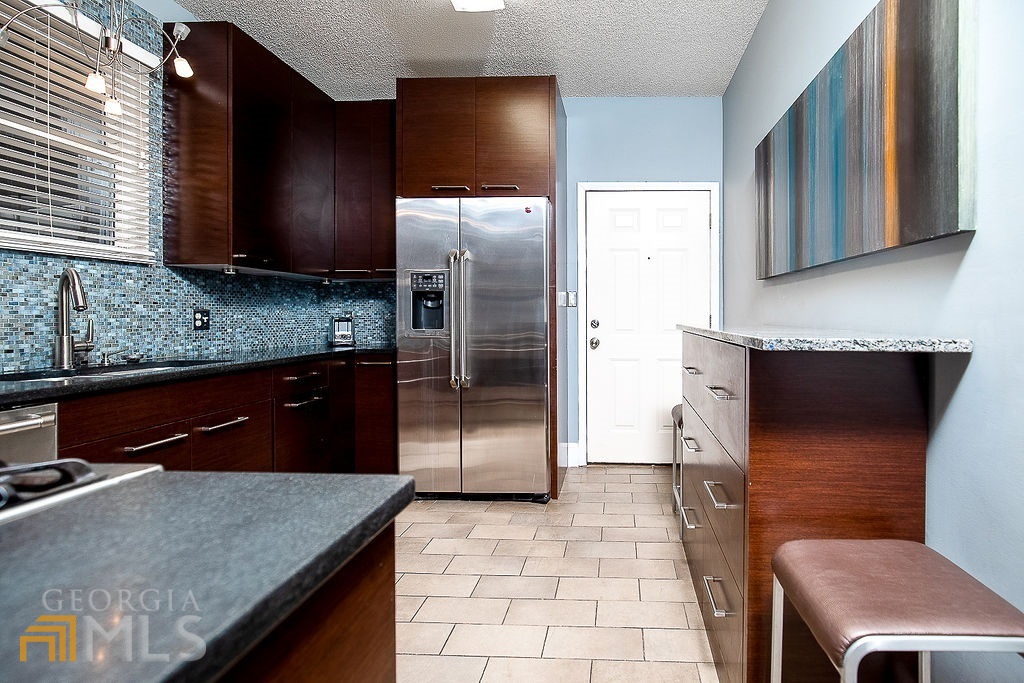570 Reed Street Southeast Atlanta, GA 30312 - Photo 1 of 11 a kitchen with stainless steel appliances granite countertop a refrigerator a stove and a sink with wooden cabinets