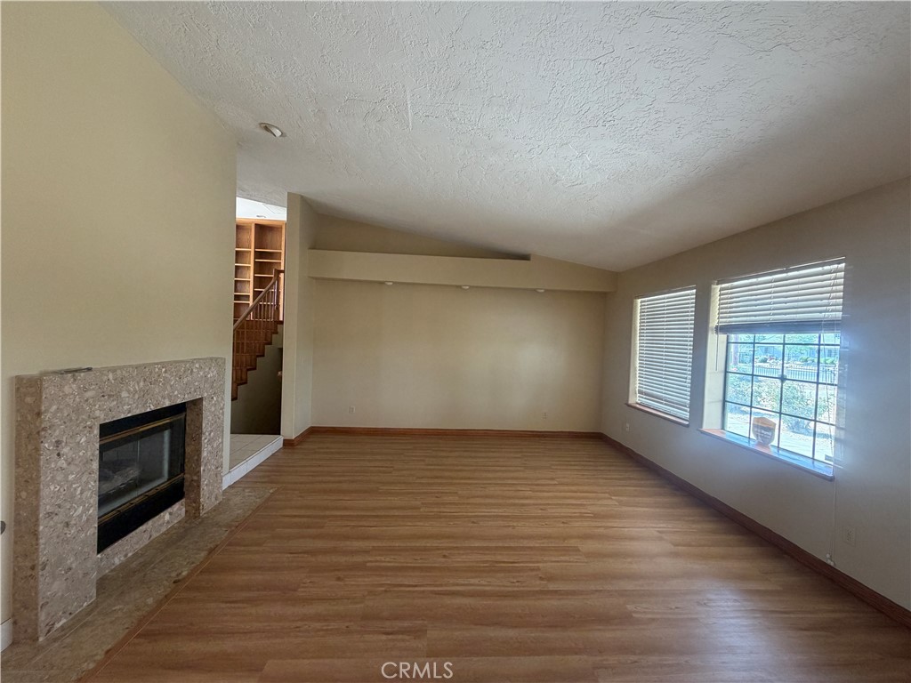 19609 Seneca Road Apple Valley, CA 92307 - Photo 13 of 37 an empty room with wooden floor and fireplace