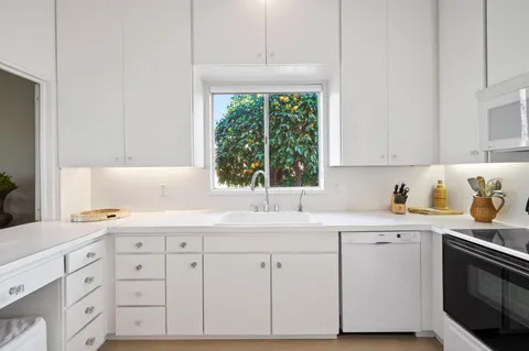 a kitchen with cabinets appliances a sink and a window