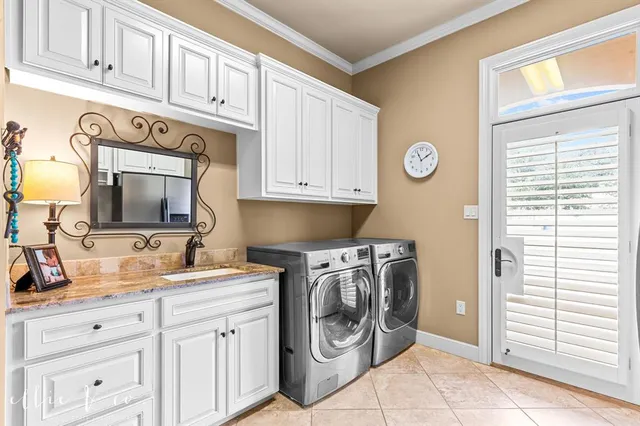 a utility room with stainless steel appliances white cabinets and a window
