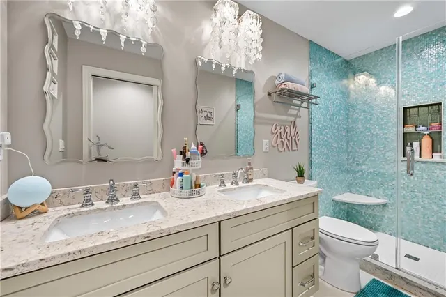 a bathroom with a granite countertop double vanity sink mirror and toilet