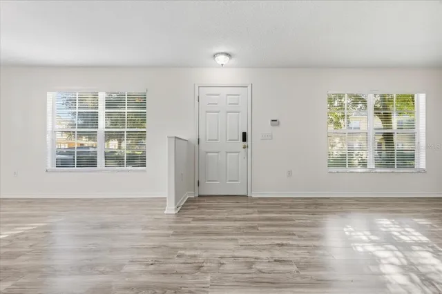 a view of an empty room with wooden floor and windows