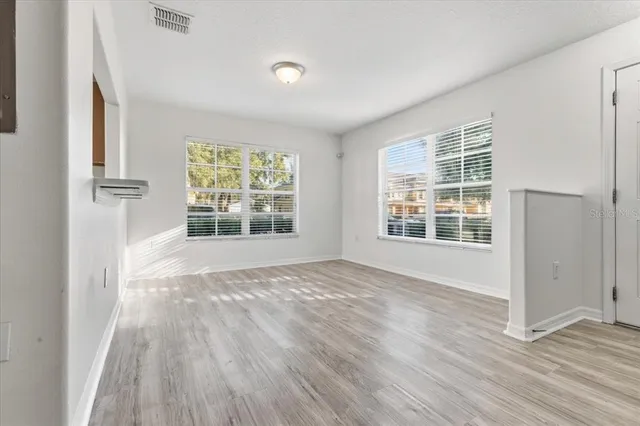 an empty room with wooden floor and windows