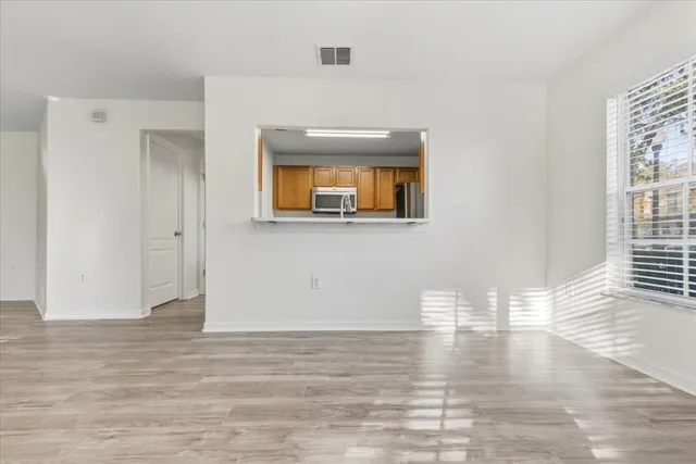 a view of an empty room with wooden floor and a window