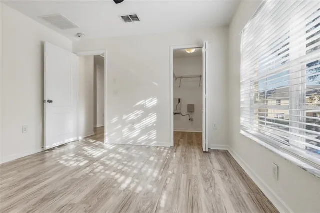 a view of empty room with wooden floor and fan