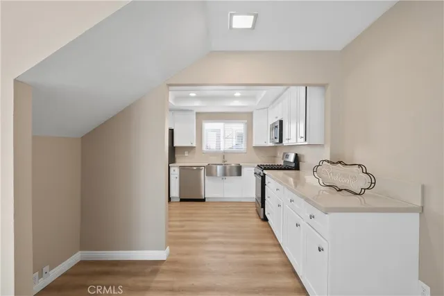 a large kitchen with a sink and dishwasher a stove with wooden floor