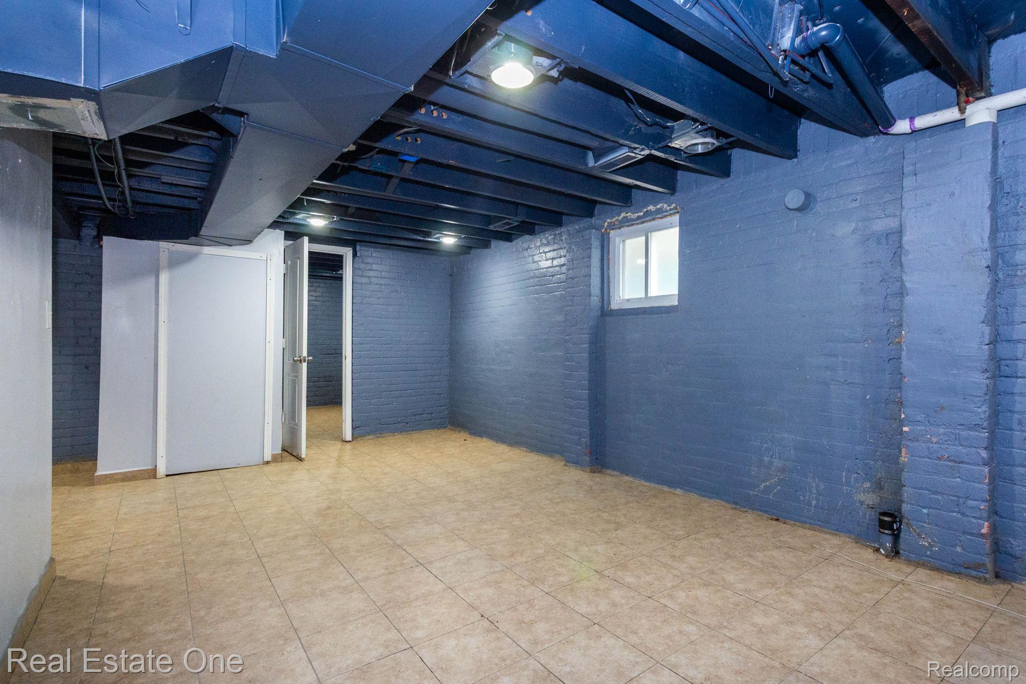 5485 Springwells Street Detroit, MI 48210 - Photo 38 of 47 Spacious room featuring tile flooring, exposed ceiling beams, painted brick walls, recessed lighting, and a small window